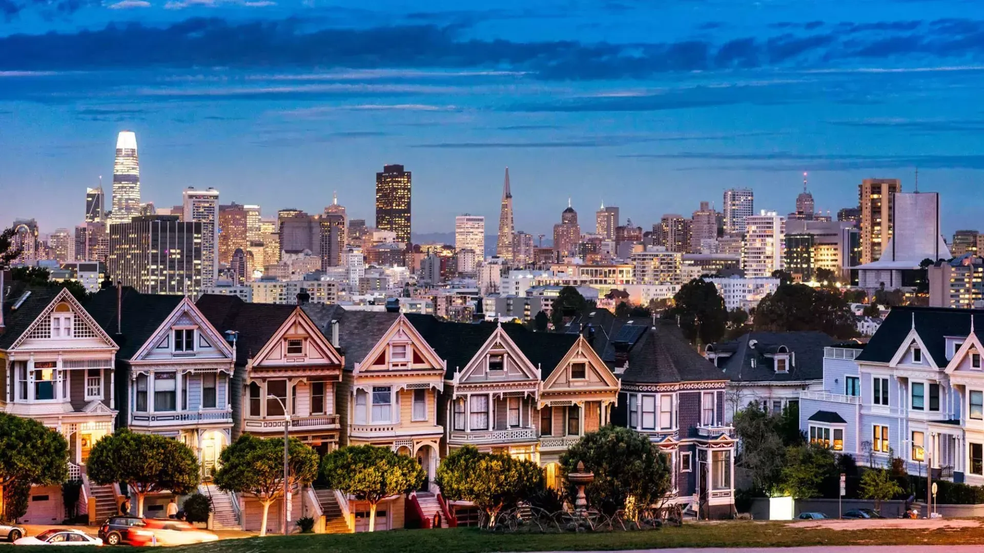 Les célèbres Painted Ladies d'Alamo Square sont photographiées devant l'horizon de San Francisco au crépuscule.