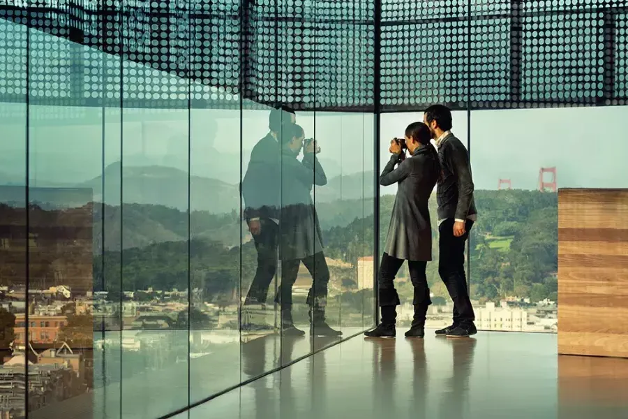 Deux personnes regardent à travers les parois de verre du De Young Museum de San Francisco.